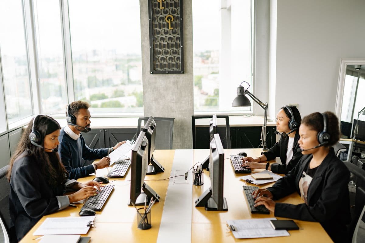 Team mit Headsets bearbeitet gleichzeitig eingehende Kundenanfragen an mehreren Bildschirmen