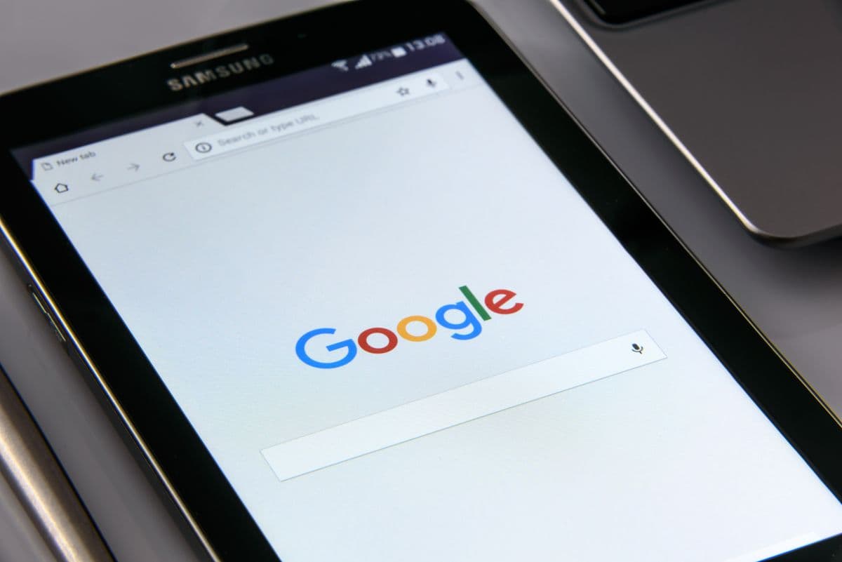 Tablet zeigt die Google-Startseite mit Suchfeld neben einem Smartphone